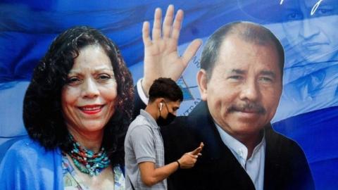 A man checks his phone while walking by a banner promoting Nicaraguan President Daniel Ortega and Vice President Rosario Murillo as presidential election campaigning begins, in Managua, Nicaragua, September 25, 2021