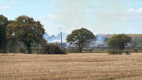 Crop fields and burnt out barns in the distance