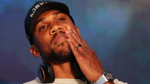 Anthony Joshua touches his face during a press conference