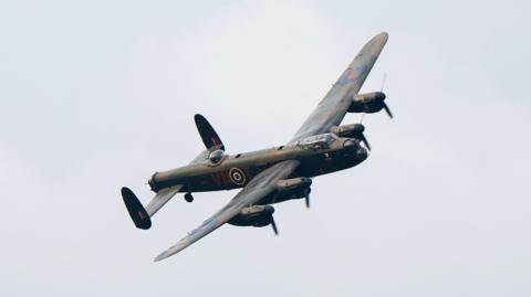 A dark green military aircraft in the sky