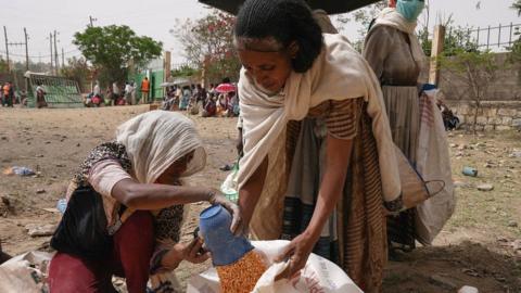 Woman scooping up lentils at aid distribution point near Mekelle