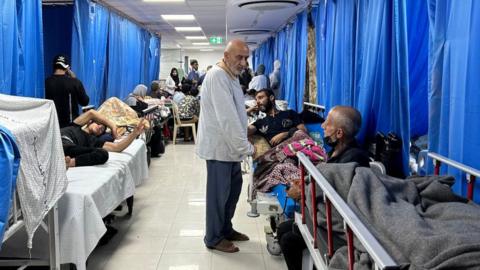 A man wanders among hospital patients lying on beds in Gaza's Al-Shifa hospital