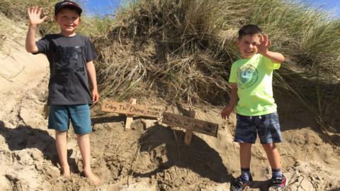 Flynn, 7, and Teddy, 4, with signs in sand dunes