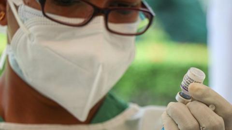 A health worker extracts pfizer covid-19 vaccine form a vial