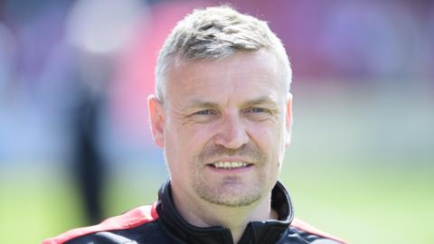 New Bristol City boss Michael Skubala looking on smiling before an EFL match.