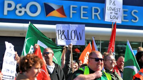 People hold placards during a demonstration against the sacking of 800 P&O workers, outside the P&O offices at the Port of Hull, eastern England, on 18 March 2022