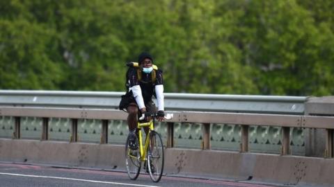 A cyclist wearing a protective mask crosses Westminster Bridge on 7 May, 2020 in London