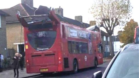 Social media image shows red double decker bus with the roof torn off. It is parked on a residential street and a child wearing a coat can be seen next to it.