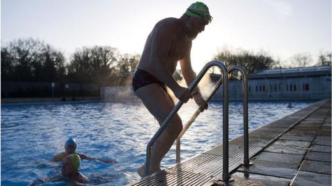 A swimmer gets out of the ice cold water at Tooting Bec Lido