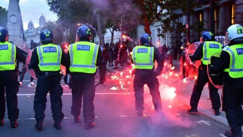 A flare hits the pavement as police and protesters clash at the anti-racism demonstration in London