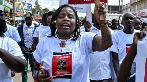 Activists and athletes carry banners and chant slogans as they march through Eldoret, western Kenya, on September 13, 2024, to demonstrate against the murder of women in Kenya after Rebecca Cheptegei lost her life