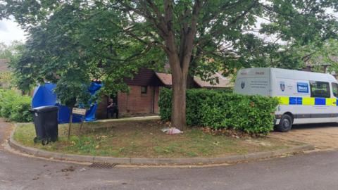 A police van and tent outside a house