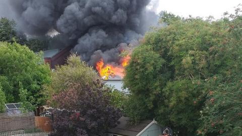 Flames and smoke coming from rooftops during car workshop fire in St Albans, as seen from nearby home