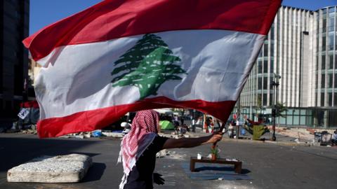 An anti-government protester holds up a Lebanese flag at a camp in Beirut (30 October 2019)