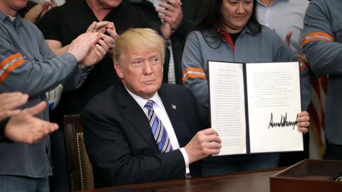 President Trump, holding up a memo he has just signed imposing tariffs on steel and aluminium