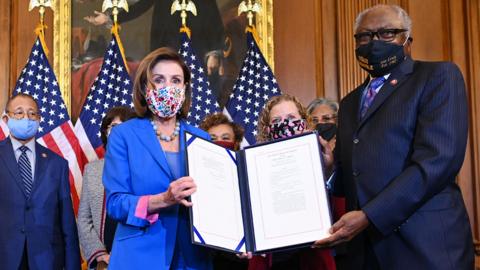 Speaker of the US House of Representatives Nancy Pelosi and Representative Jim Clyburn hold up a signed bill to fund the US government avoiding a federal shutdown with other members of the House or Representatives at the US Capitol in Washington, DC, on 30 September 2021