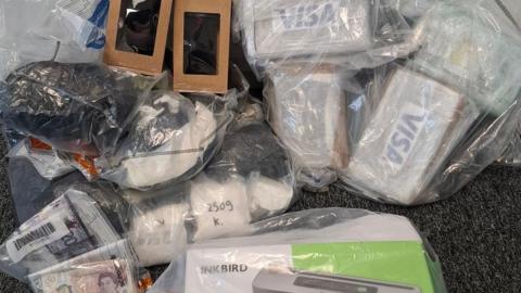 The picture shows a number of items in clear plastic bags, including cash