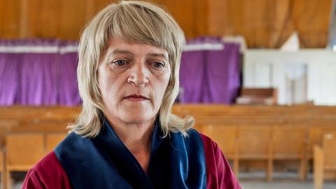 Tetyana Potapenko, a middle-aged blonde woman, looks pensive in maroon prison overalls  