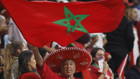 Moroccan fan in hat waves a flag