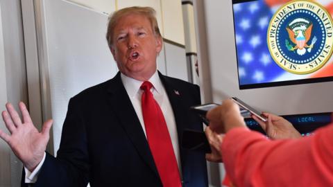 US President Donald Trump speaks to the press aboard Air Force One