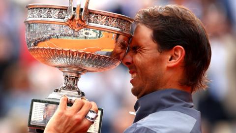 Nadal brings the trophy to his forehead