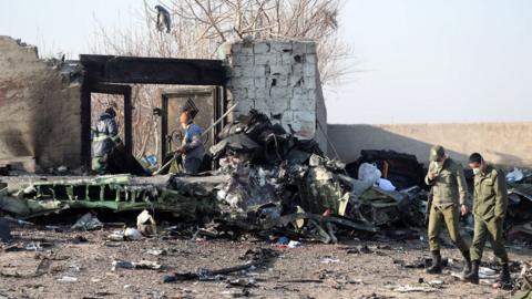 People stand near the wreckage after a Ukrainian plane carrying 176 passengers crashed near Imam Khomeini airport in Tehran on January 8, 2020