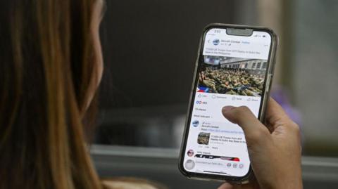 A woman reads the news on her smartphone