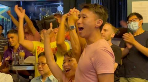 Singaporeans cheering and holding hands