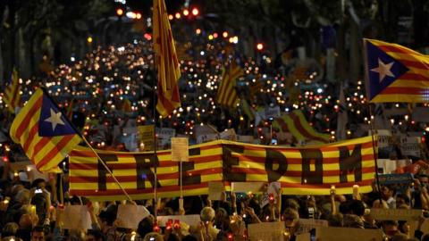 People hold a giant Estelada (pro-independence Catalan flag) reading "Freedom" during candle-lit demonstration in Barcelona against the arrest of two Catalan separatist leaders on October 17, 2017.