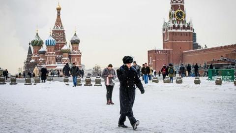 A serviceman walks in front of St Basil's Cathedral and the Kremlin