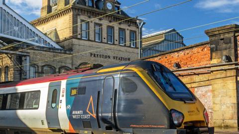 Train sat outside Preston rail station, with the station building in the background