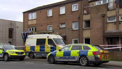 Police vehicles at the scene of the fire at a flat on Clooney Terrace
