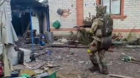 Soldier holding gun near buildings