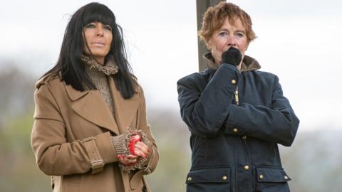 Claudia Winkleman and Celia Imrie stand next to each other outside wearing coats in the latest episode of The Traitors