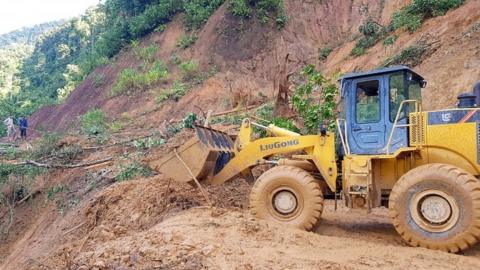 An excavator clears a road to allow access to a village that was hit by a landslide in Nam Tra My district in Quang Nam province