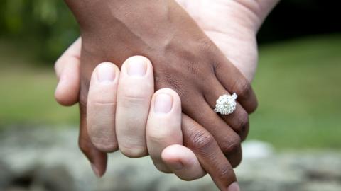 A black and white hand with a wedding ring