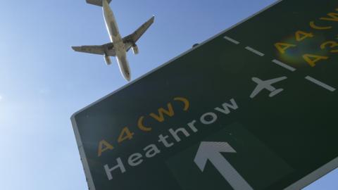 Plane flies over Heathrow road sign