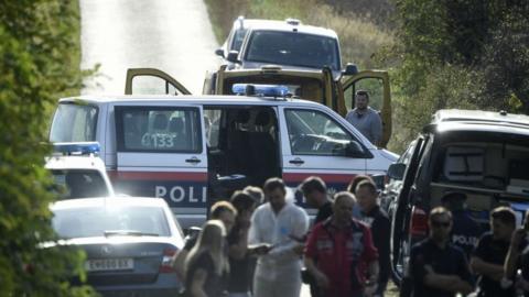 Austrian police are seen near the Austrian-Hungarian border near Siegendorf, Burgenland, Eisenstadt district, on October 19, 2021, where two migrants were discovered dead inside a van (yellow vehicle) during a control.