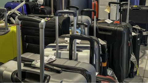 Piles of Lost unclaimed luggage at airport as supply chain and employee strike action causes delays and baggage handling shortages. Passengers waiting hours to reclaim their belongings