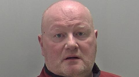 Simon Garnett looks at the camera in a police mugshot