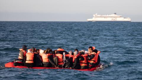 Migrants packed tightly onto a small inflatable boat attempt to cross the English Channel near the Dover Strait