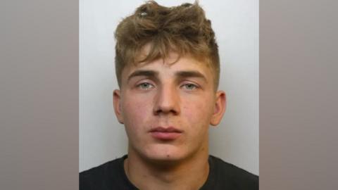Mugshot of Kasper Stankiewicz who was convicted of Alfie Gray's death. He has short dark blonde hair and blue eyes. He is pictured against a plain, light background, looking straight at the camera with a blank expression.