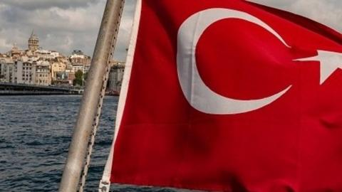 A Turkish flag flying from the rear of a Bosporus ferry with Istanbul in the background