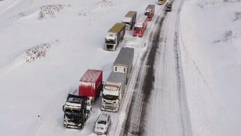 Long queue of lorries stuck in snow on motorway
