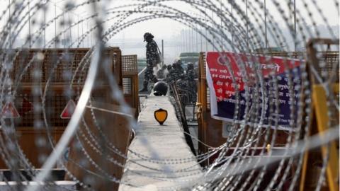 Indian Security personnel are seen through barbed wire placed by security personnel as farmers protest at the Delhi Ghazipur Border near New Delhi, India, 02 February 2021.