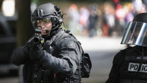 A police officer shoots non-lethal rounds at demonstrators in Portland (04 June 2017)