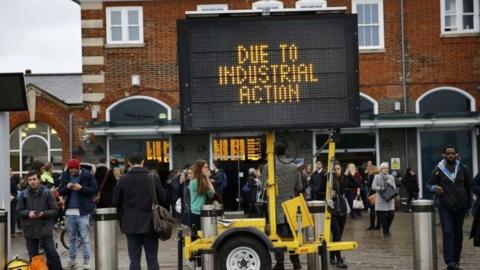 Commuters wait outside Clapham Junction during a tube strike in London