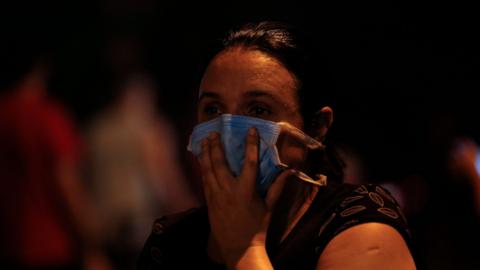 A woman covers her face with a surgical mask to protect herself from the smoke during a fire at the Badim private Hospital in Tijuca neighborhood, Rio de Janeiro, Brazil, on September 12, 2019