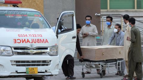 A body of a Covid-19 victim is moved to an ambulance in Rawalpindi, Pakistan