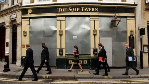 City workers walk past a closed down pub in London's financial distric